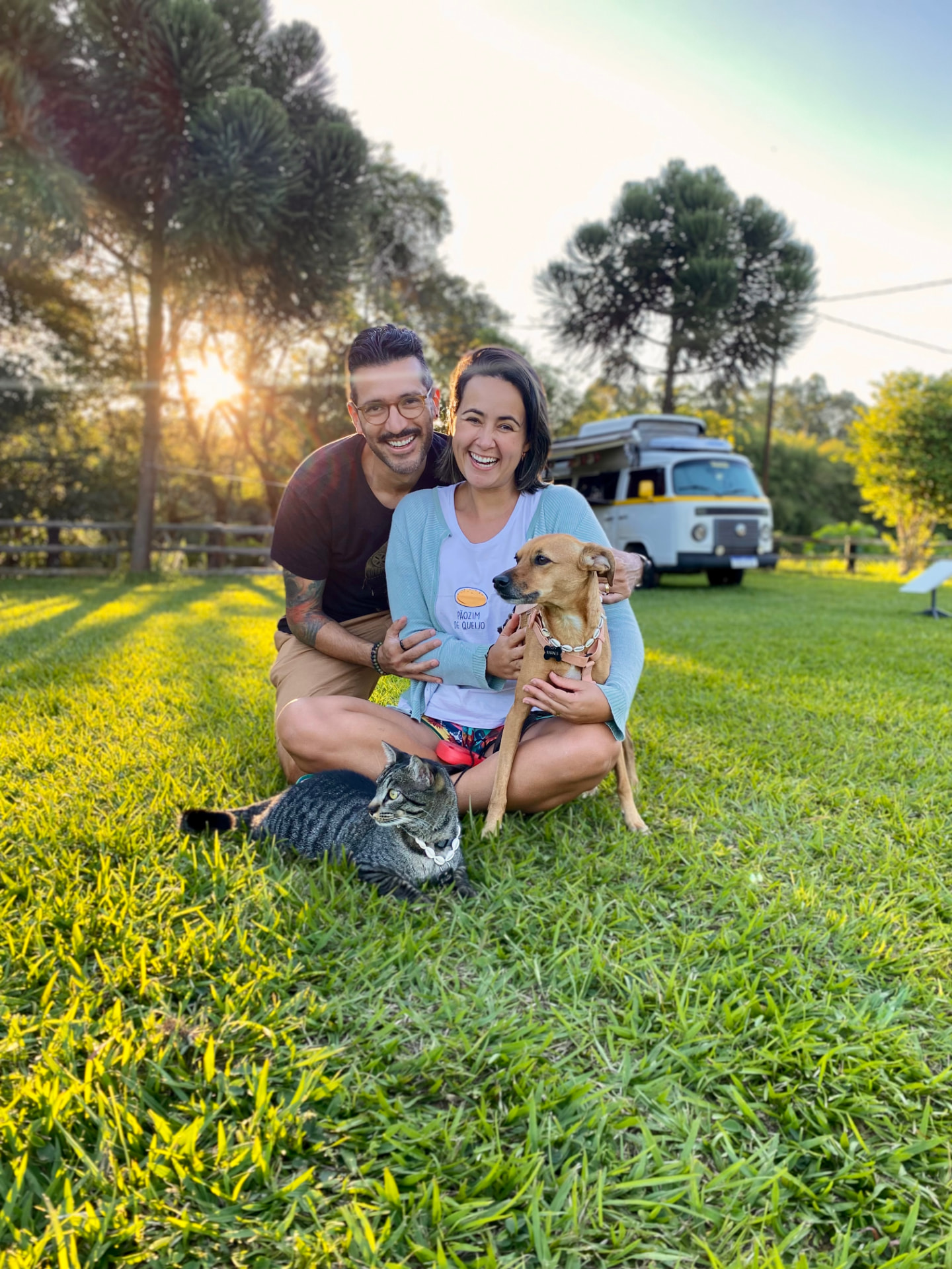 Daniel e Ana com a cachorrinha Mari e o gato Sivuca, ao pôr do sol, com a Kombi Home ao fundo
